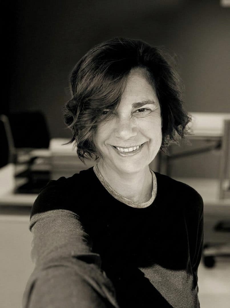 Black and white portrait of a smiling woman with short, wavy dark hair.